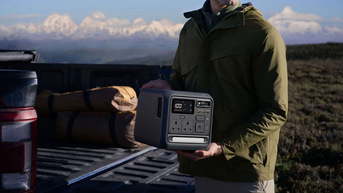 Person lifting a DJI Power 1000 Mini from a pickup truck bed in the mountains